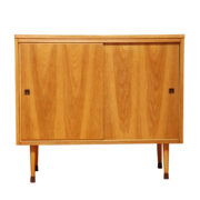 Dość wysoka orzechowa szafka na drewnianych toczonych nogach z dwoma półkami i suwanymi drzwiczkami, UP Závody Rousínov, Czechosłowacja, lata 60.