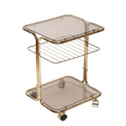 Mobilny nieduży i lekki stolik/wózek barowy na metalowej konstrukcji z giętych rurek w kolorze złotym z dwoma nakładanymi szklanymi dymionymi blatami i ażurową półką, Niemcy, lata 80.
